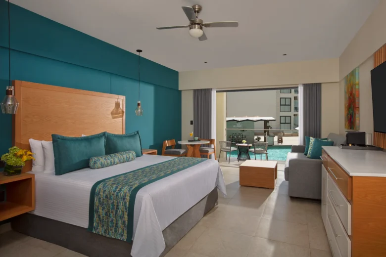 Preferred Club Junior Suite Pool View with king bed and furnished balcony at Dreams Cozumel Cape Resort & Spa overlooking the pool.
