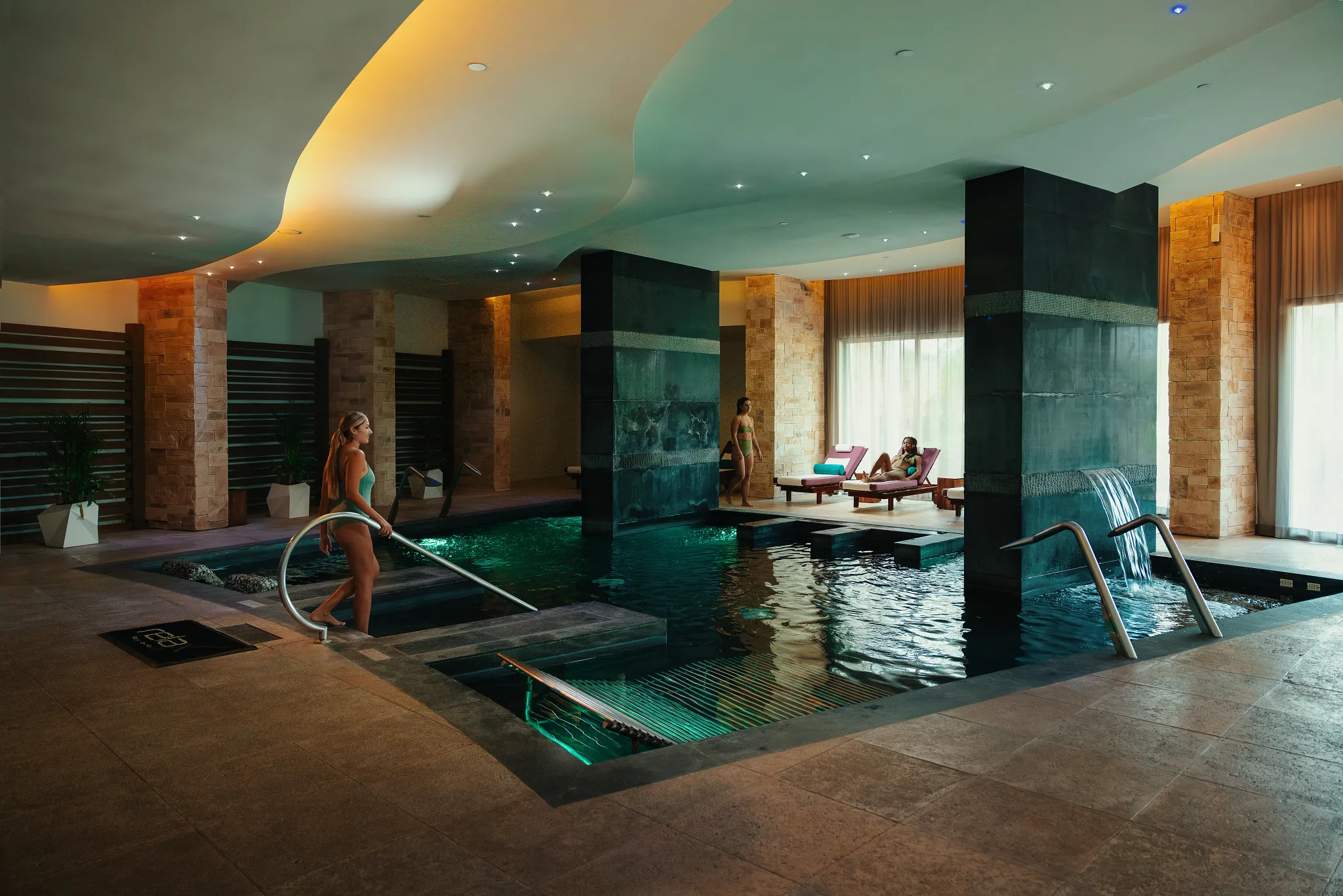 Guests enjoying the indoor hydrotherapy circuit pool at the spa at Breathless Riviera Cancun, featuring water jets and wellness-focused amenities.