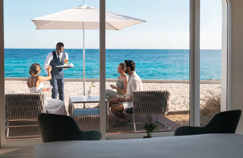 Guests enjoying beachfront drinks and service with ocean views at Dreams Curaçao Resort, Spa & Casino.