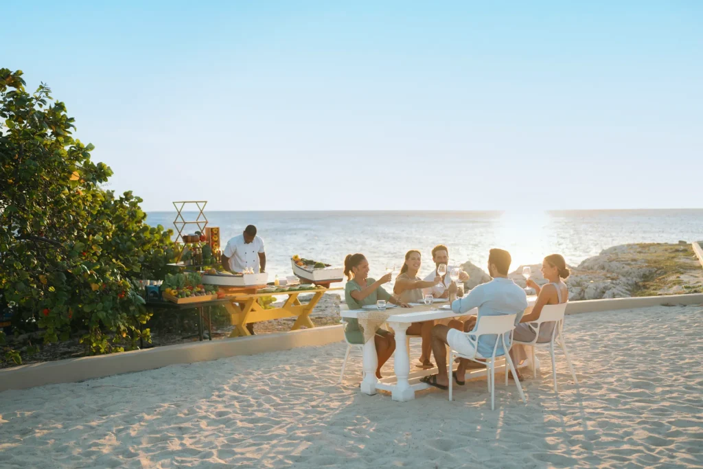 Group enjoying a beachfront dinner at sunset at Dreams Curaçao Resort.
