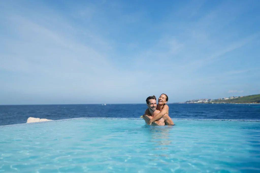 Couple embracing in an infinity pool overlooking the ocean at Dreams Curaçao Resort.