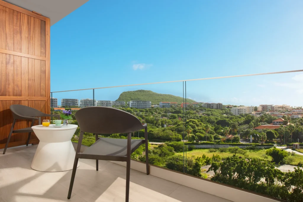 Private furnished balcony with chairs and island view at Deluxe Island View room in Dreams Curaçao Resort.
