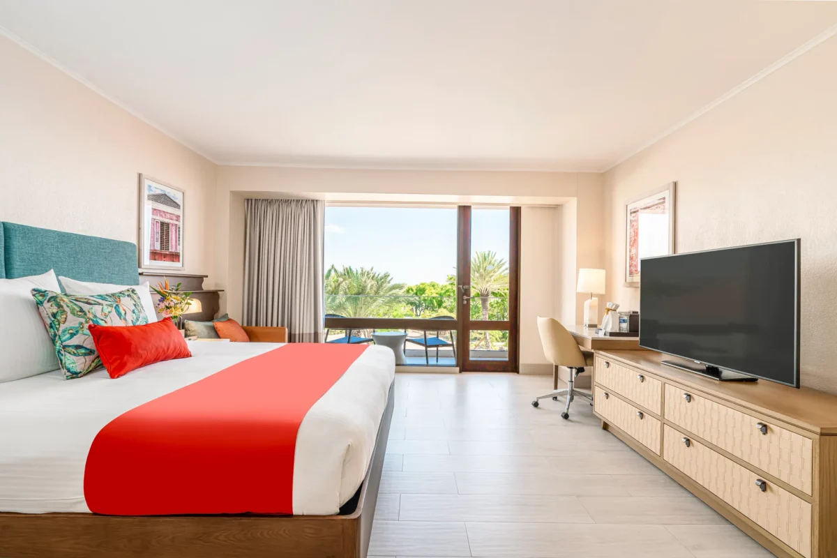 Deluxe Island View room with king bed and private balcony at Dreams Curaçao Resort overlooking lush island scenery.