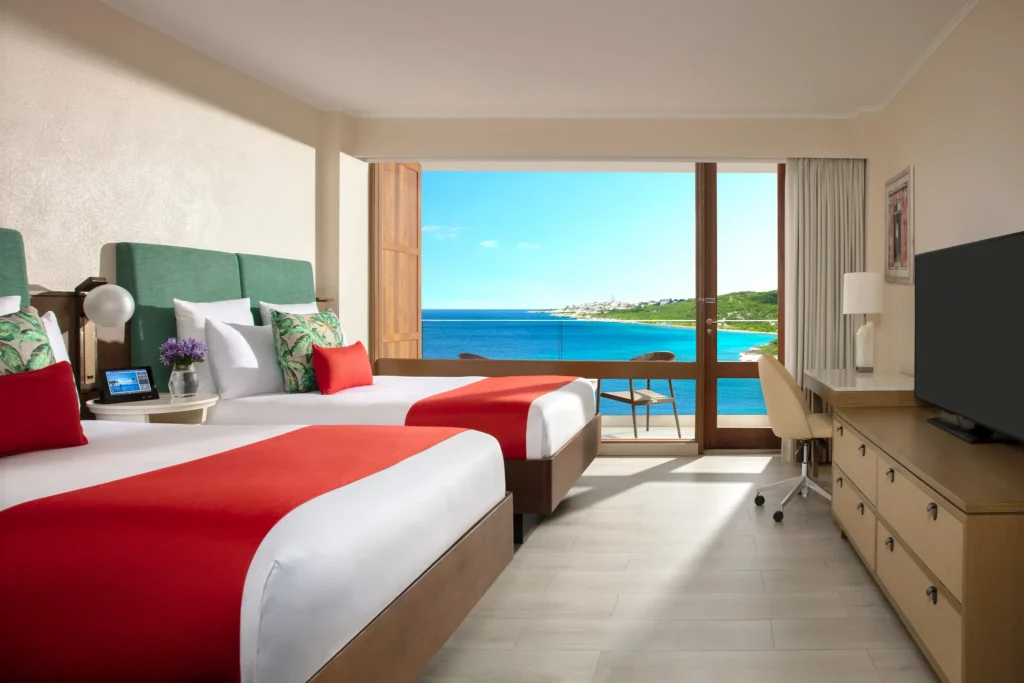 Deluxe Ocean View room with two double beds and balcony overlooking turquoise ocean at Dreams Curaçao Resort.
