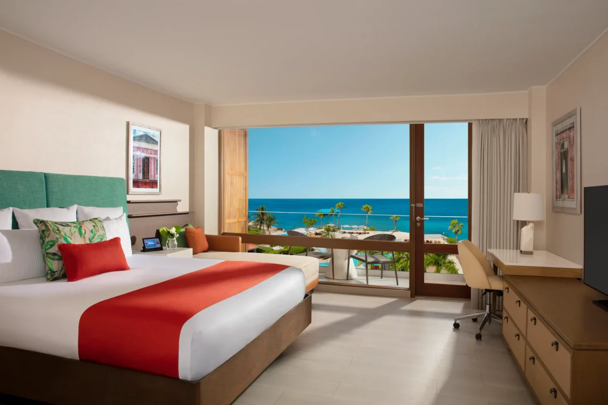 Deluxe Pool View room with king bed and private balcony overlooking pool and ocean at Dreams Curaçao Resort.