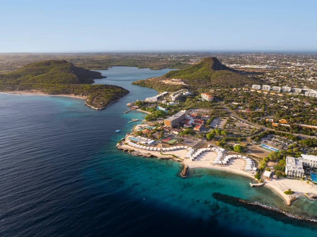 Wide aerial view of Dreams Curaçao Mare beachfront with white cabanas and turquoise shoreline.