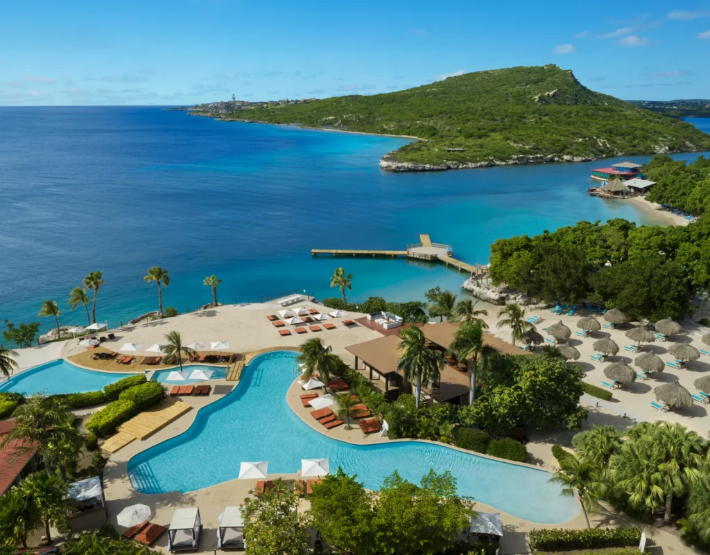 Modern beachfront bungalows lined along the shore at Dreams Curaçao Resort with ocean views.