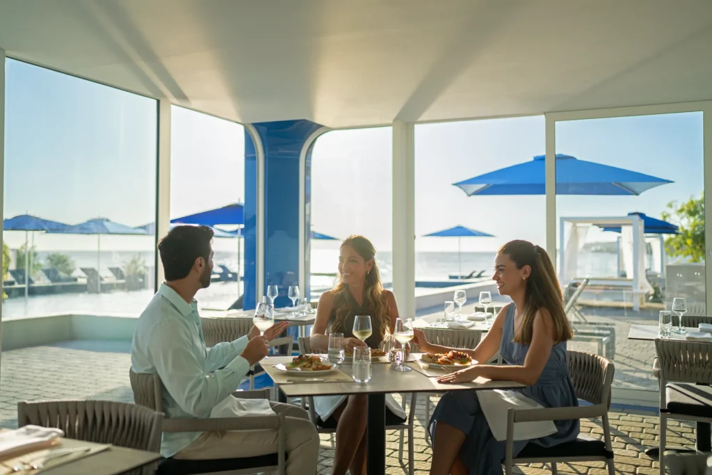 Guests dining indoors with ocean views at Dreams Curaçao Resort restaurant.