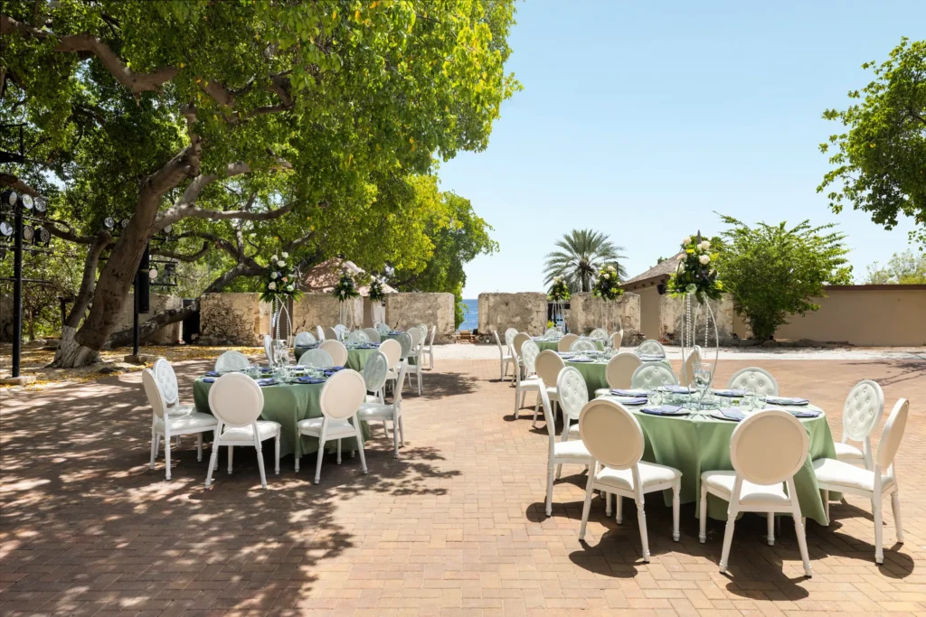 Elegant outdoor wedding reception setup with round tables and floral centerpieces at Dreams Curaçao Resort.