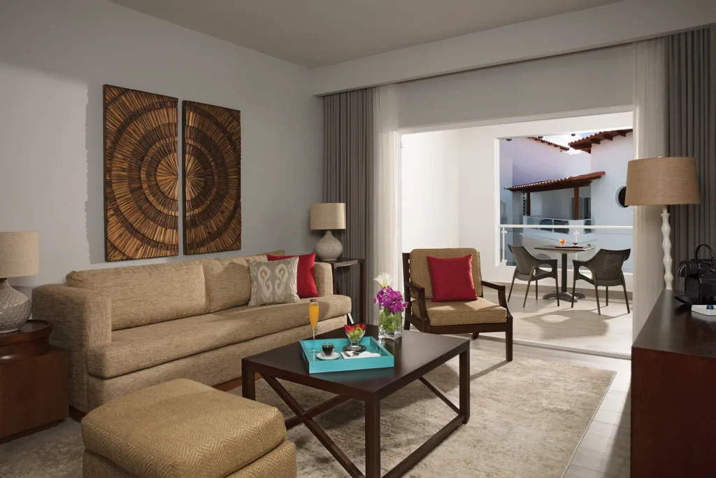 Preferred Club Suite Tropical View living area with sofa and furnished balcony at Dreams Dominicus La Romana.