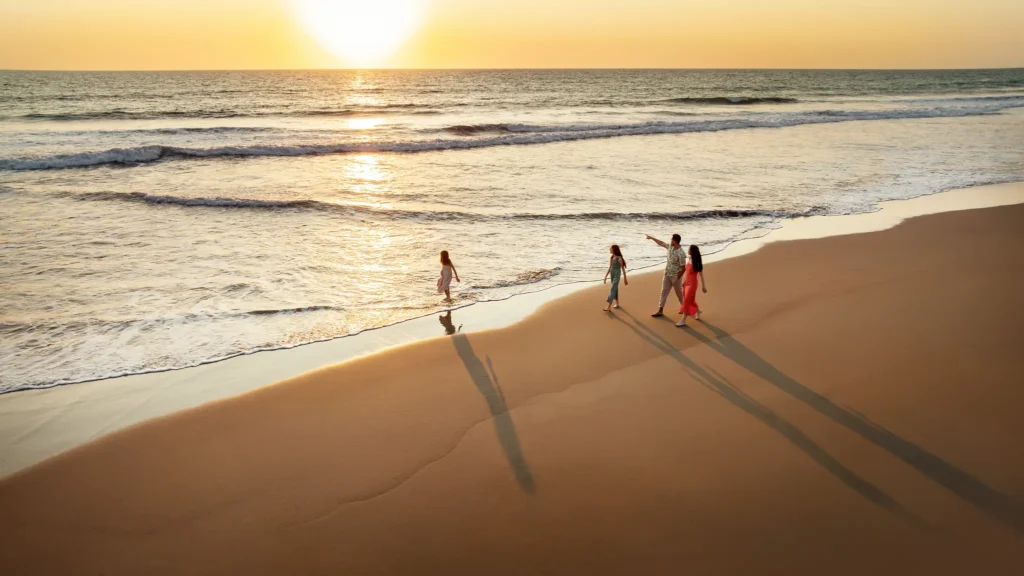 Family walking along the beach at sunset near Dreams Estrella del Mar Mazatlan Golf & Spa Resort.