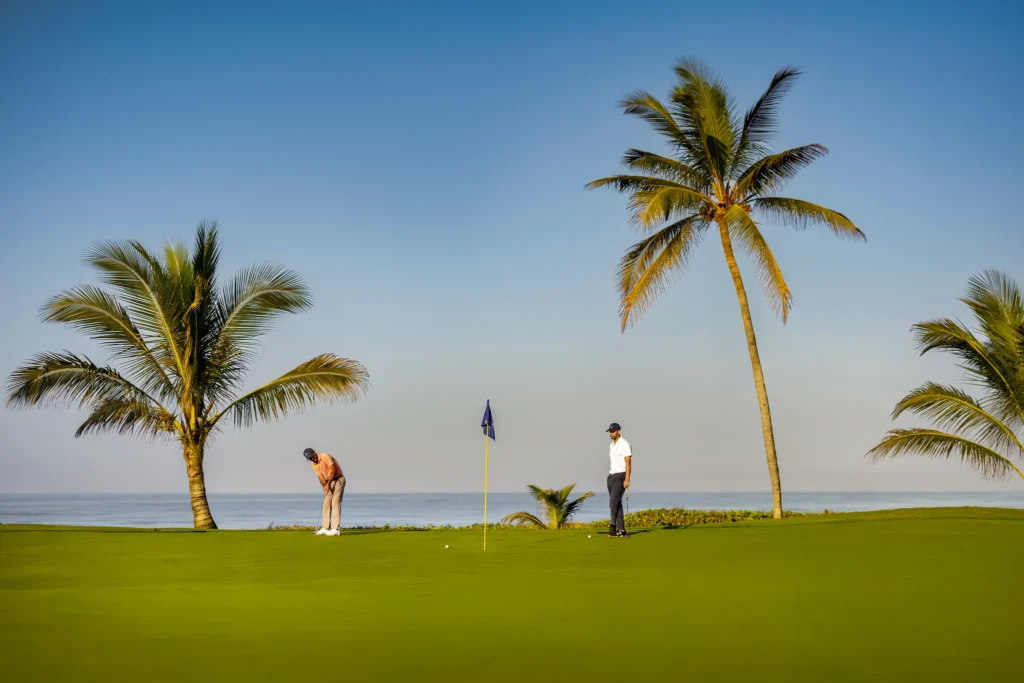 Golfers practicing on a seaside putting green at Dreams Estrella del Mar Mazatlan Golf & Spa Resort.