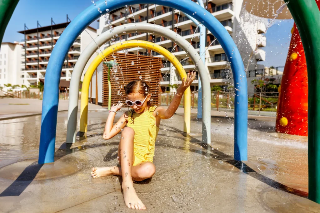 Child playing in a colorful splash park water feature at Dreams Estrella del Mar Mazatlan Golf & Spa Resort.
