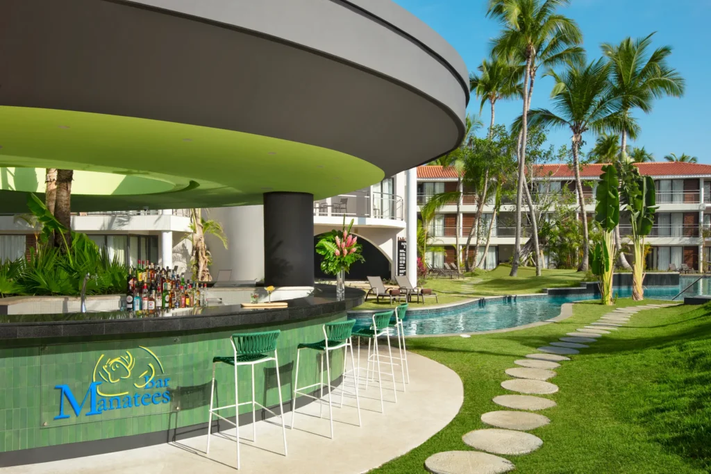 Manatees swim-up bar at Dreams Flora Resort & Spa featuring a poolside bar, tropical landscaping, and guests enjoying cocktails in the water.