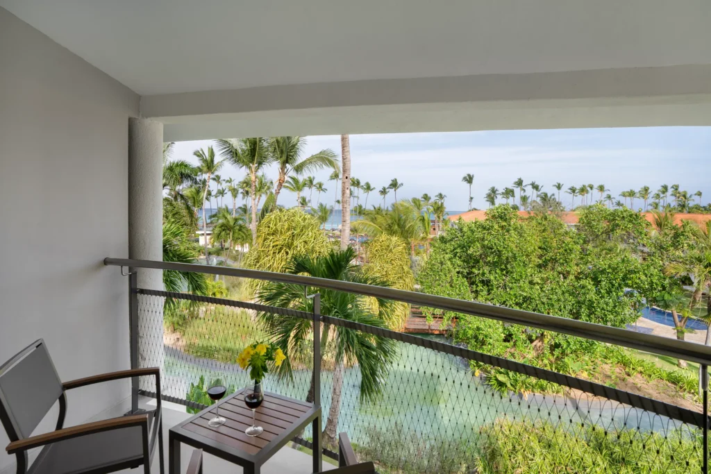 Preferred Club Junior Suite Partial Ocean View balcony with tropical garden and ocean glimpse at Dreams Flora Resort & Spa.