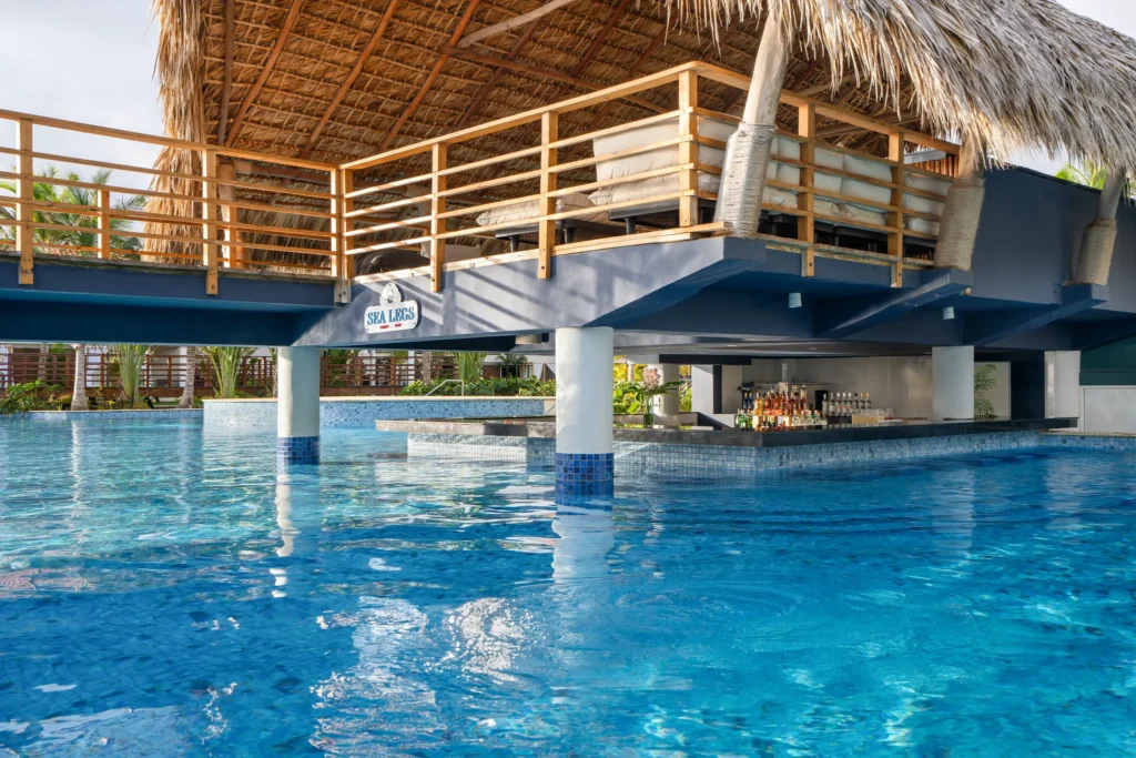 Sea Legs swim-up bar at Dreams Flora Resort & Spa featuring a poolside bar under a thatched roof with tropical resort surroundings.