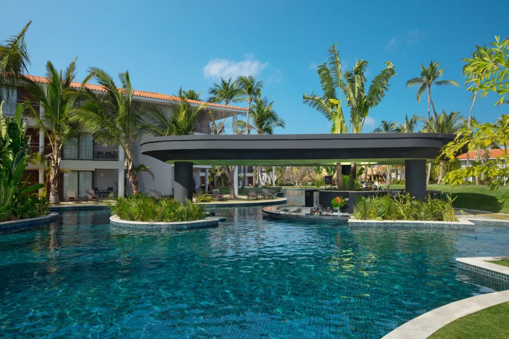 Sugar Reef pool bar at Dreams Flora Resort & Spa featuring a swim-up bar, tropical landscaping, and expansive resort pool.
