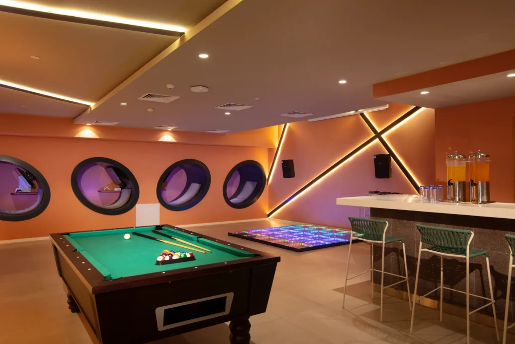 The Zone Teens Bar at Dreams Flora Resort & Spa featuring a modern lounge, pool table, neon dance floor, and interactive teen space.