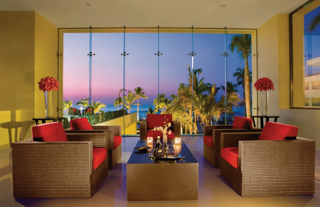Elegant cigar lounge with ocean views inside Dreams Huatulco Resort & Spa at sunset.