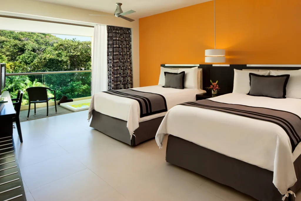 Deluxe Tropical View with Hot Tub room featuring two double beds at Dreams Huatulco Resort & Spa with lush tropical surroundings.