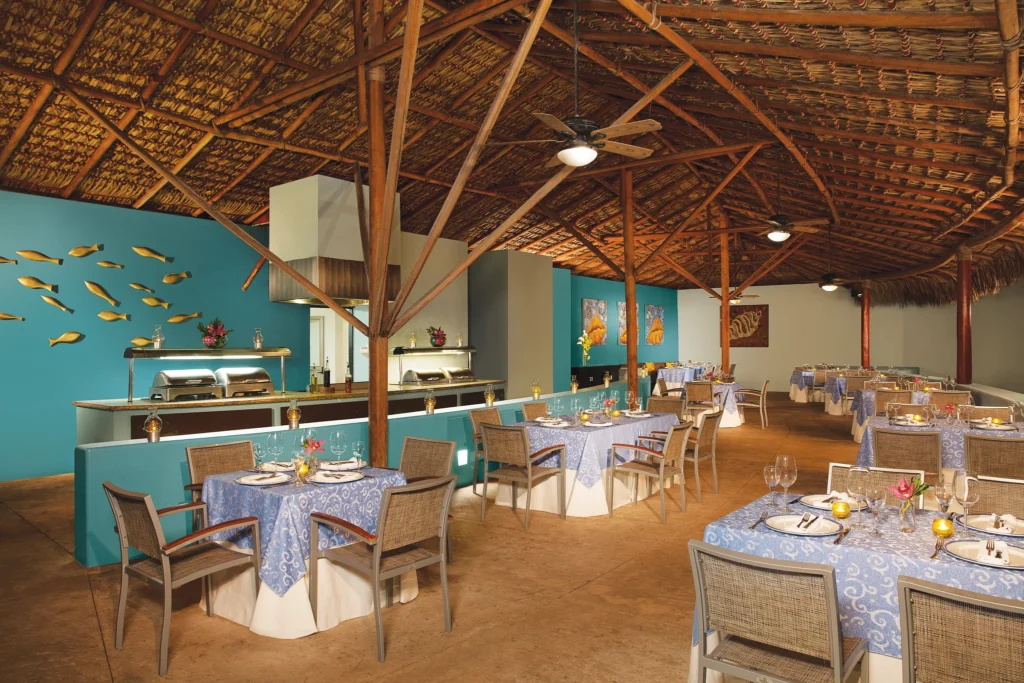 Oceana seafood restaurant at Dreams Huatulco Resort & Spa featuring open-air dining, elegant table settings, and a romantic seaside ambiance.