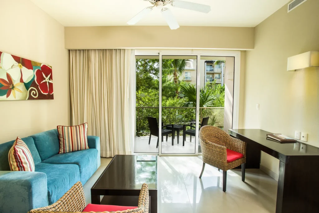 Family Suite Tropical View living area with sofa and private furnished balcony at Dreams Jade Resort & Spa.