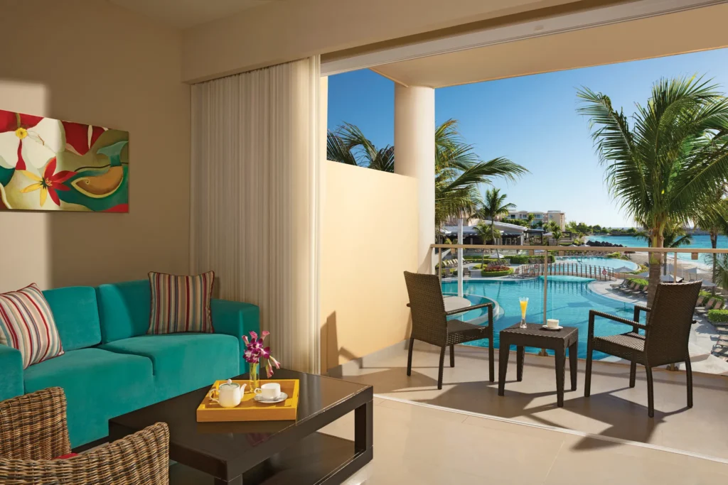 Junior Suite Ocean Front View balcony with seating area overlooking pool and ocean at Dreams Jade Resort & Spa.