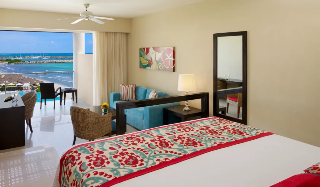Junior Suite Ocean View king bed with living area and balcony overlooking the ocean at Dreams Jade Resort & Spa.