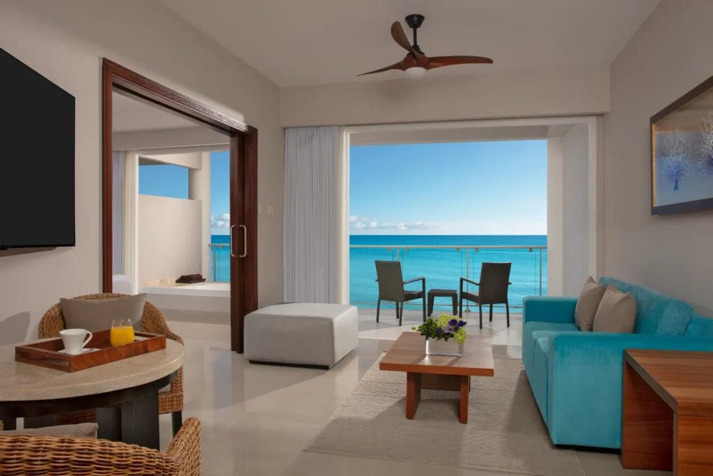 Preferred Club Suite Ocean Front living area with sofa and balcony access at Dreams Jade Resort & Spa.