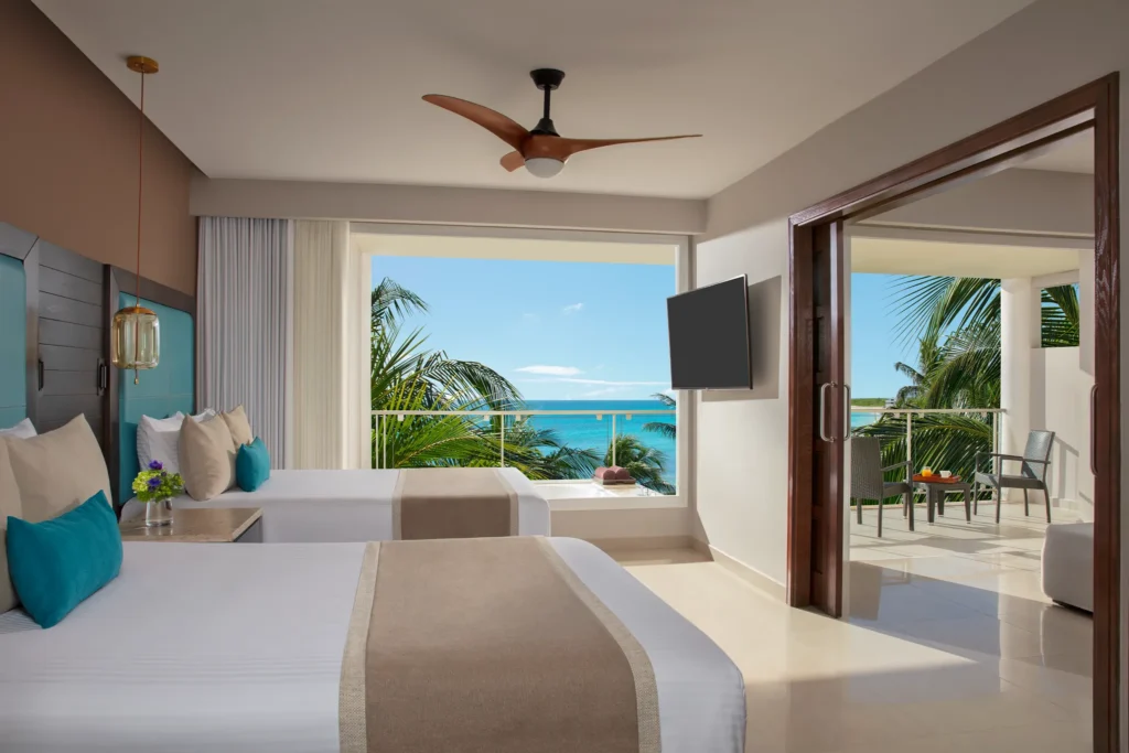 Preferred Club Suite Ocean View with two double beds and private balcony at Dreams Jade Resort & Spa overlooking the Caribbean Sea.