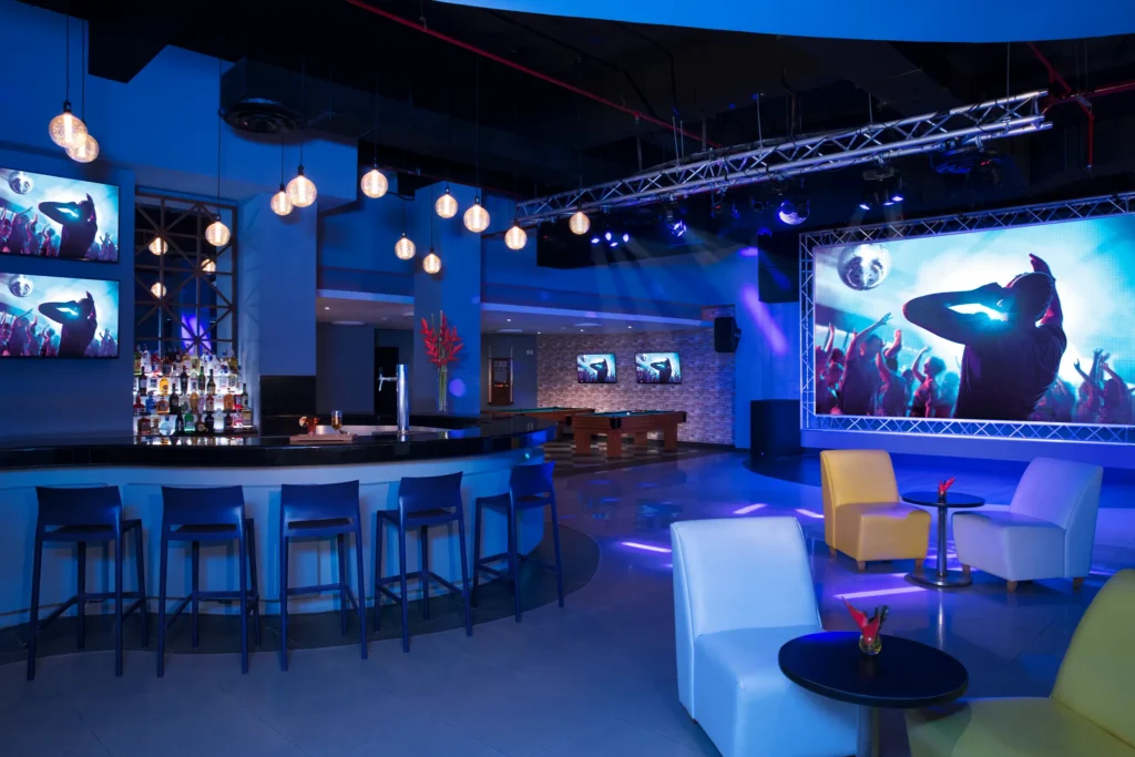 Scores sports bar at Dreams Jade Resort & Spa featuring large LED screen, DJ lighting, bar seating, and pool tables.