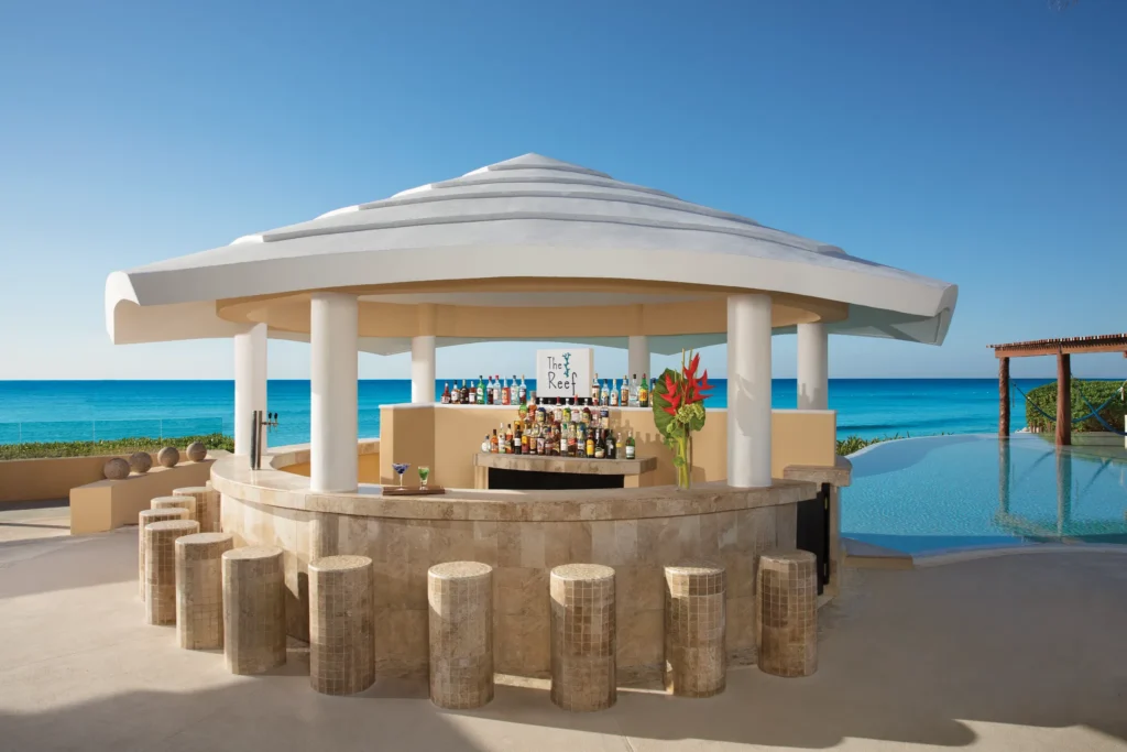 The Reef swim-up bar at Dreams Jade Resort & Spa featuring infinity pool seating, ocean views, and tropical cocktails.
