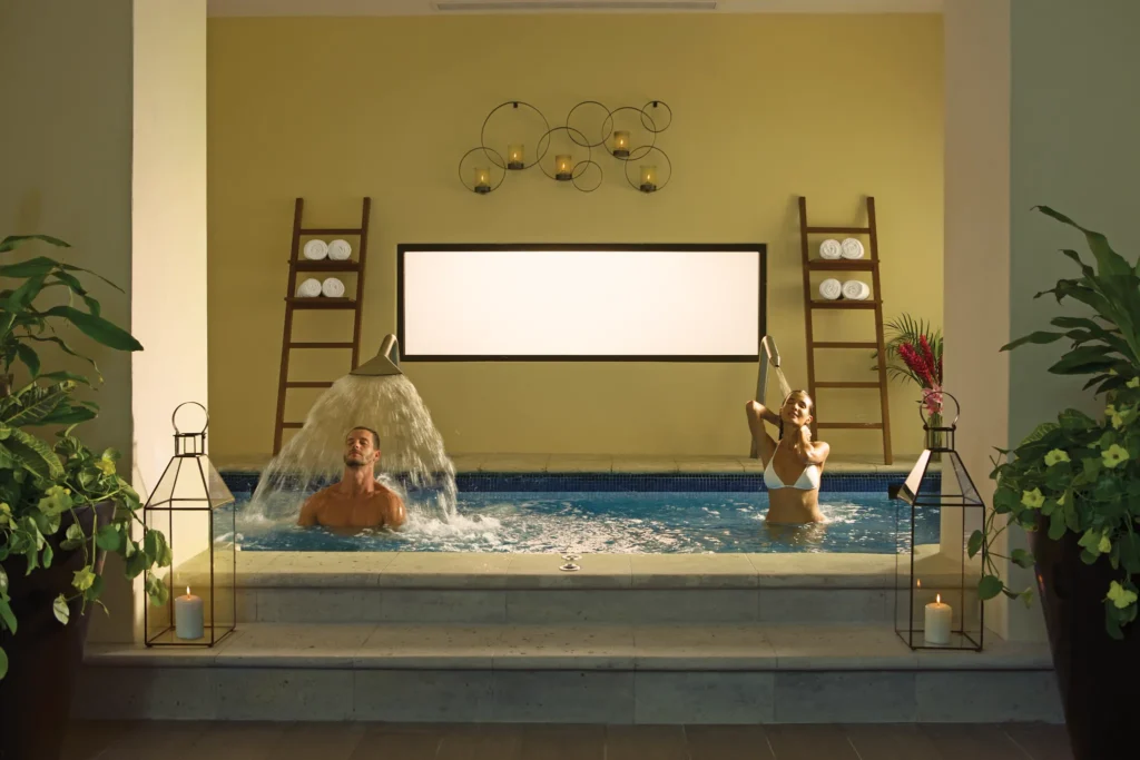 Couple enjoying hydrotherapy pool with cascading water features at the spa at Dreams Los Cabos Suites Golf Resort & Spa.