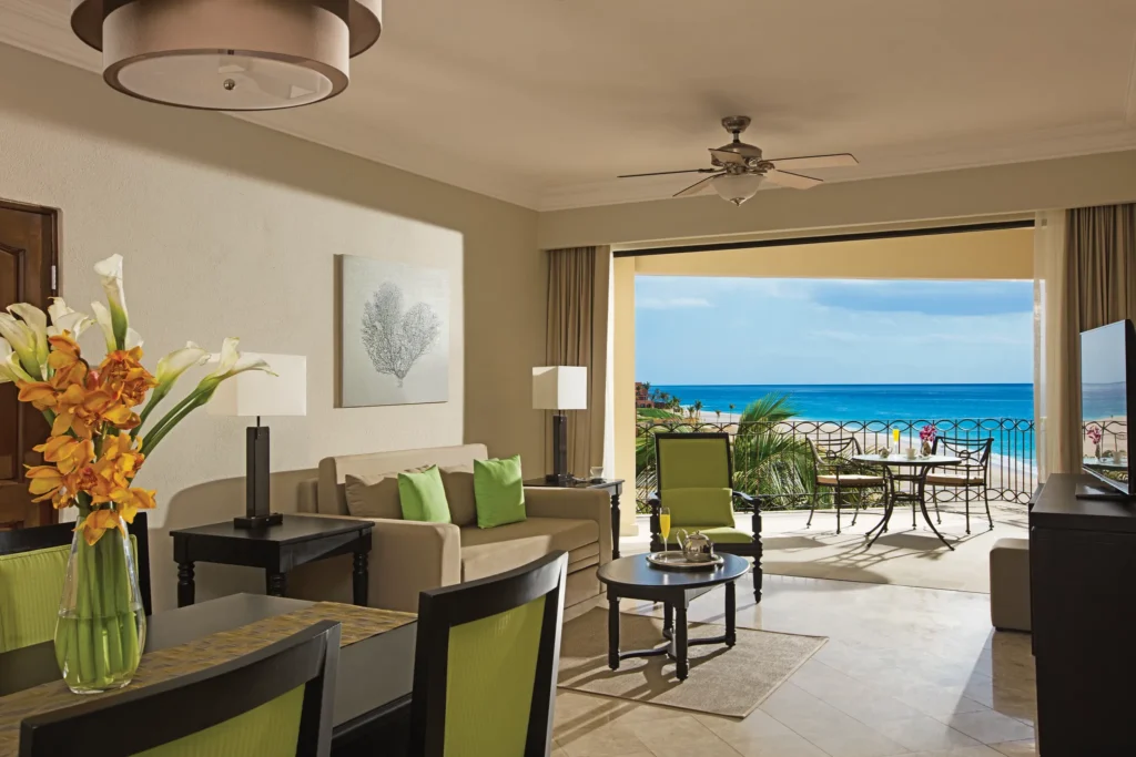 Family Junior Suite Ocean View living and dining area with ocean-view balcony at Dreams Los Cabos Suites Golf Resort & Spa.