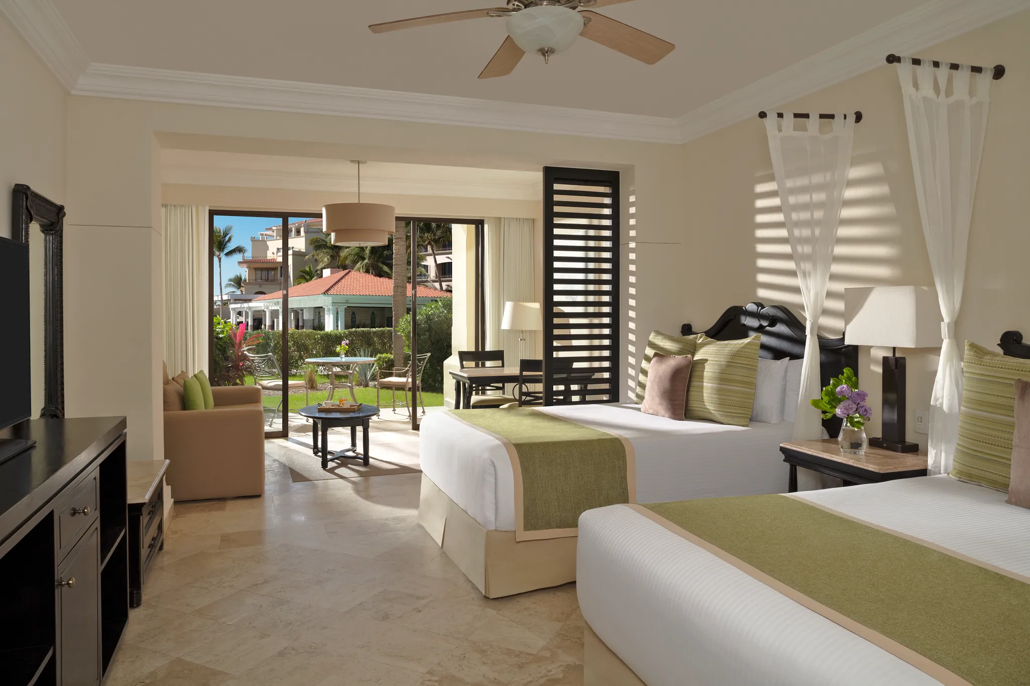 Junior Suite Garden View with two double beds and private terrace at Dreams Los Cabos Suites Golf Resort & Spa overlooking lush tropical gardens.