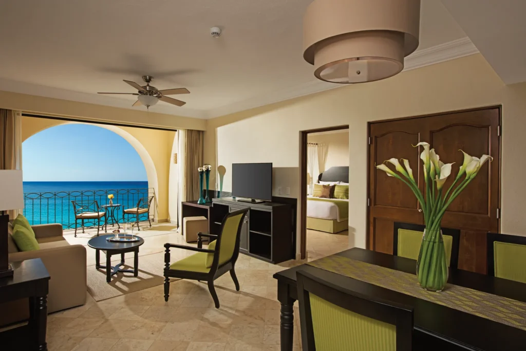Living and dining area with oceanfront balcony in the Preferred Club Family Master Two Bedroom Suite at Dreams Los Cabos.