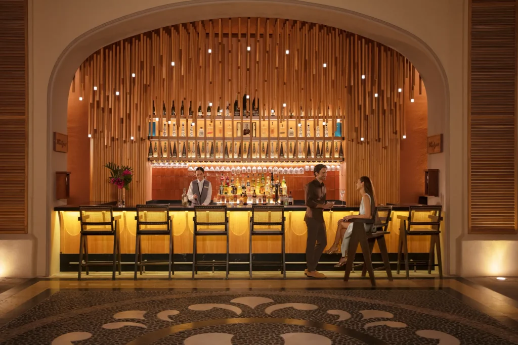 Elegant lobby bar with warm lighting and cocktails at Dreams Los Cabos Suites Golf Resort & Spa in Los Cabos.