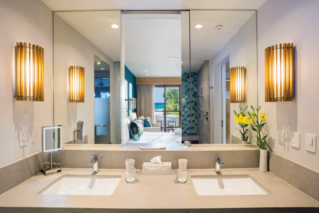 Junior Suite Partial Ocean View bathroom with double sinks and mirror reflecting ocean view at Dreams Natura Resort & Spa.