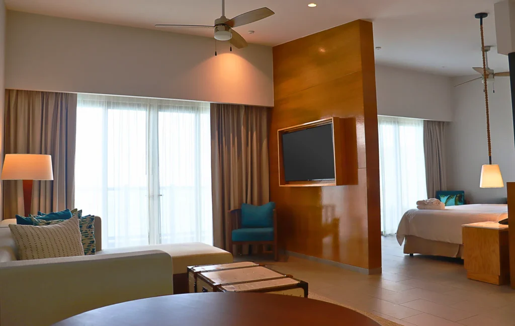 Preferred Club Master Suite Ocean Front living area with sofa and bedroom at Dreams Natura Resort & Spa.