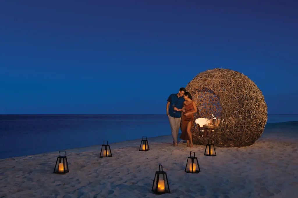 Couple enjoying a romantic candlelit beach dinner at Dreams Natura Resort & Spa in Riviera Cancun.