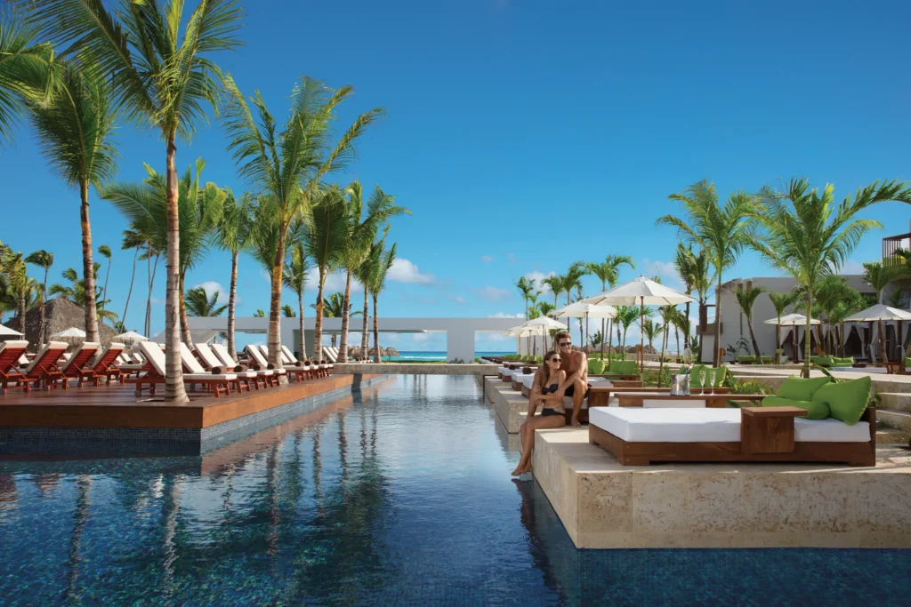 Couple relaxing on a sunbed beside a tranquil adults-only pool at Dreams Onyx Resort & Spa in Punta Cana.