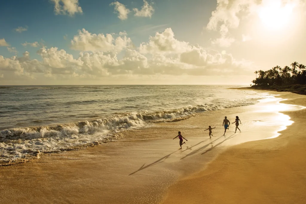 Family walking along a golden beach at sunset at Dreams Onyx Resort & Spa in Punta Cana.