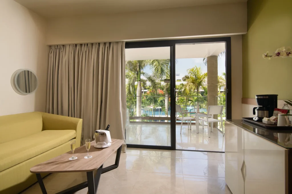 Premium Junior Suite Pool View living area with sofa, balcony, and tropical pool views at Dreams Onyx Resort & Spa.