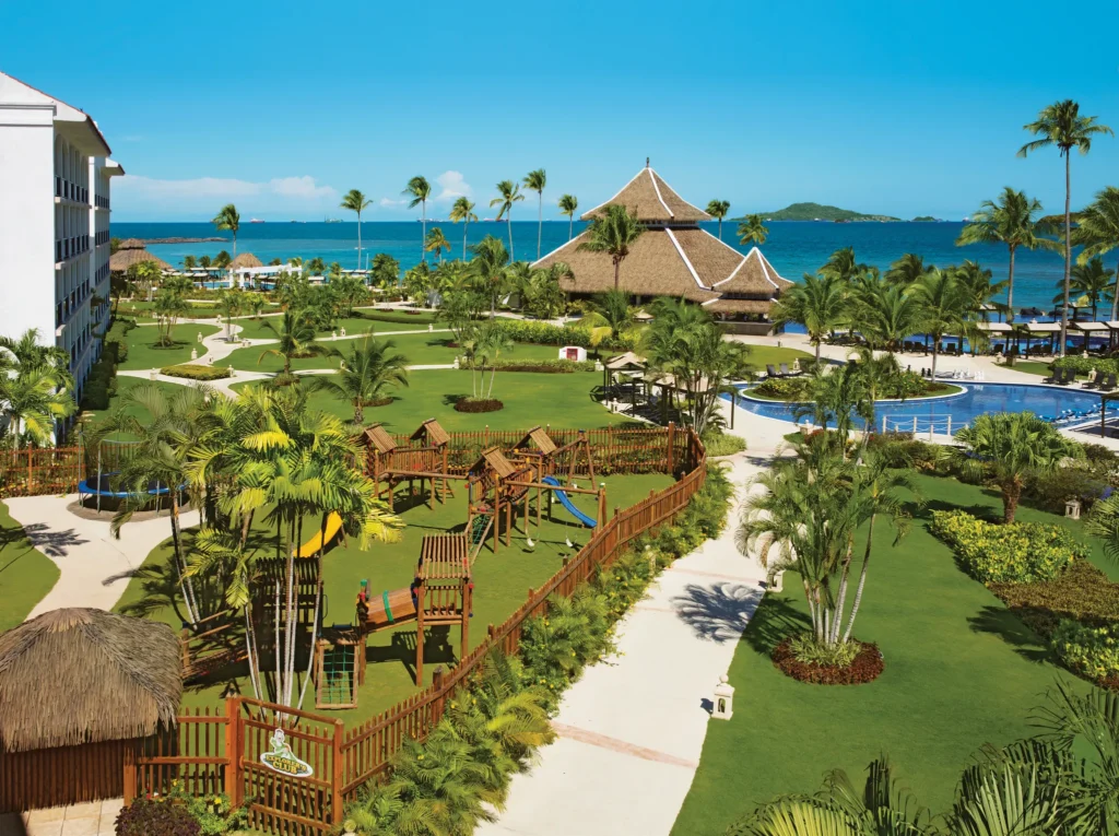 Aerial view of the family-friendly grounds and Explorers Club kids area at Dreams Playa Bonita Panama, surrounded by tropical gardens and ocean views.