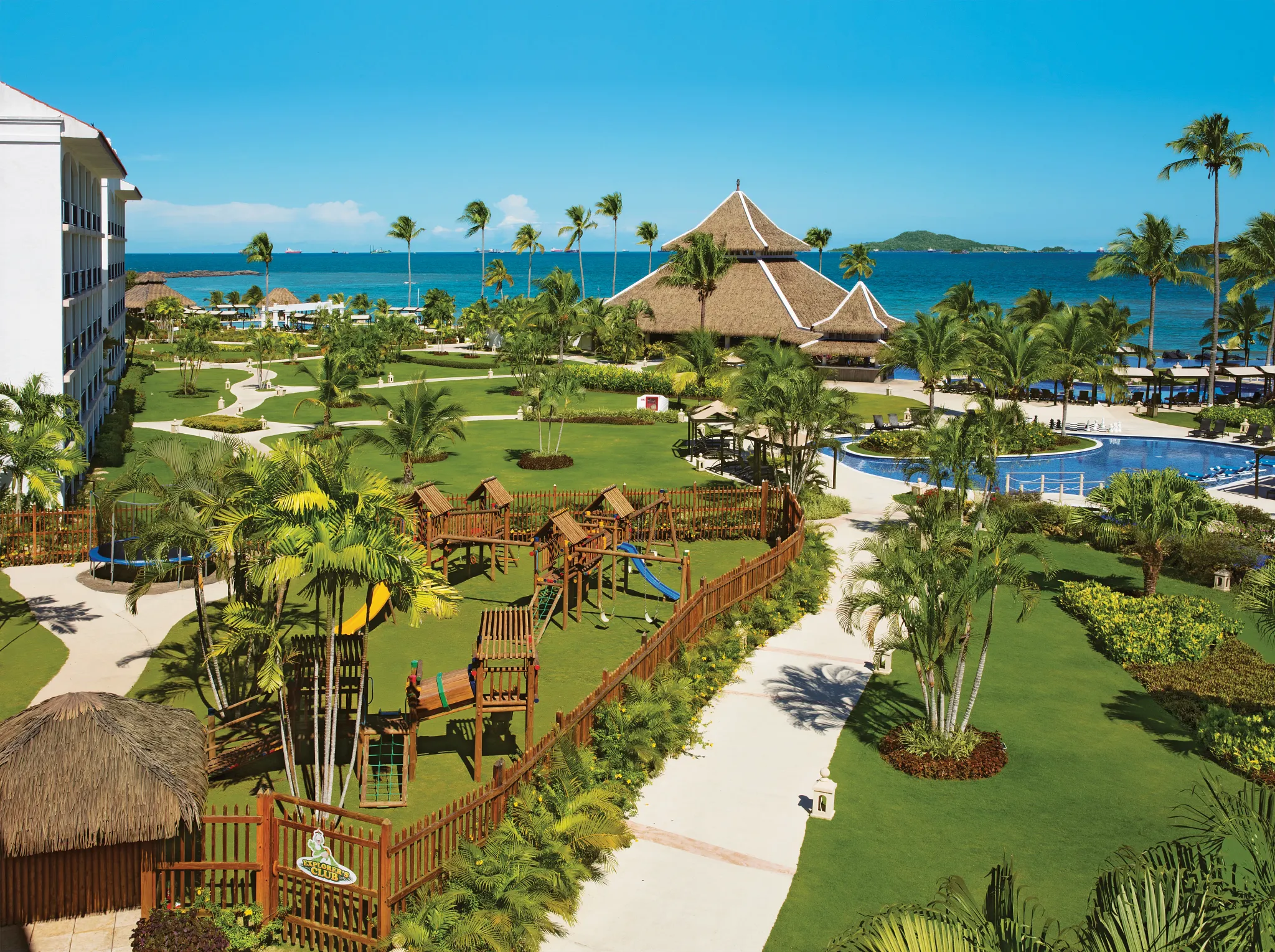 Aerial view of the family-friendly grounds and Explorers Club kids area at Dreams Playa Bonita Panama, surrounded by tropical gardens and ocean views.