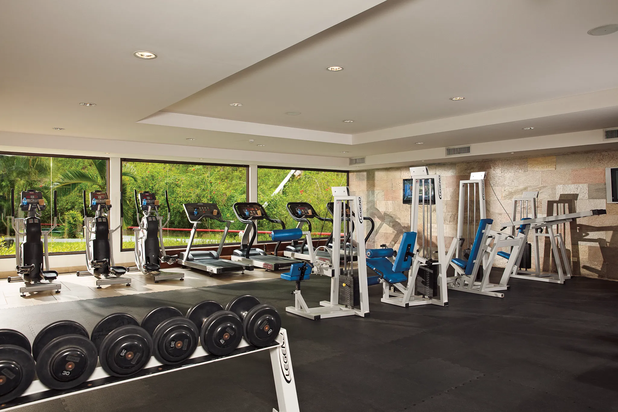 Modern fitness center with cardio machines and free weights at Dreams Playa Bonita Panama, offering a well-equipped workout space.