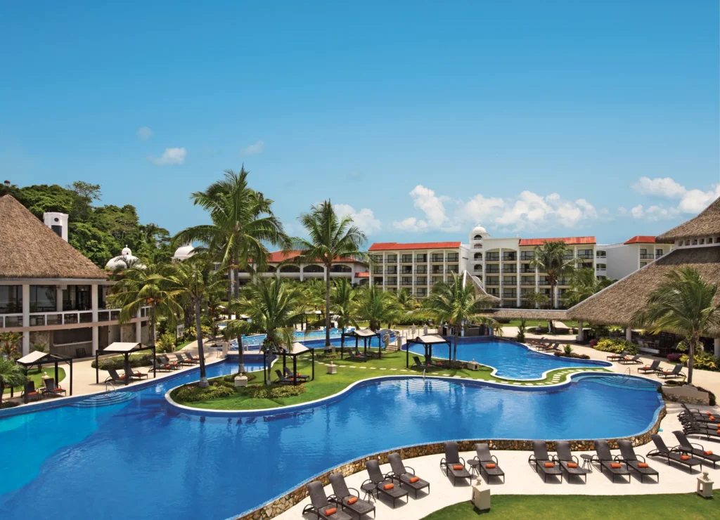 Lagoon-style infinity pool surrounded by palm trees and cabanas at Dreams Playa Bonita Panama, offering a relaxing tropical atmosphere.