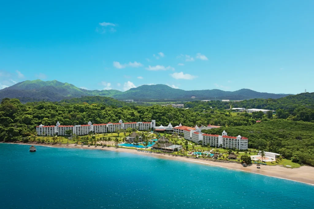 Panoramic aerial view of Dreams Playa Bonita Panama beachfront resort surrounded by lush rainforest and mountain scenery along the Pacific coast.