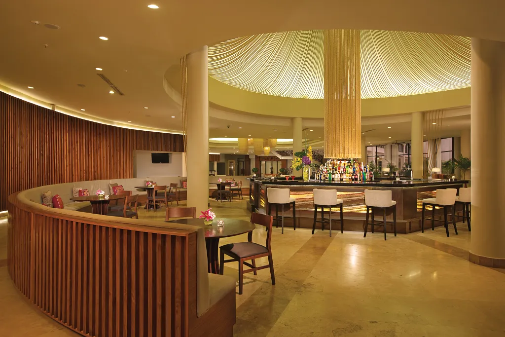 Rendezvous Lobby Bar at Dreams Playa Bonita Panama featuring a modern circular bar, stylish lounge seating, and warm ambient lighting.