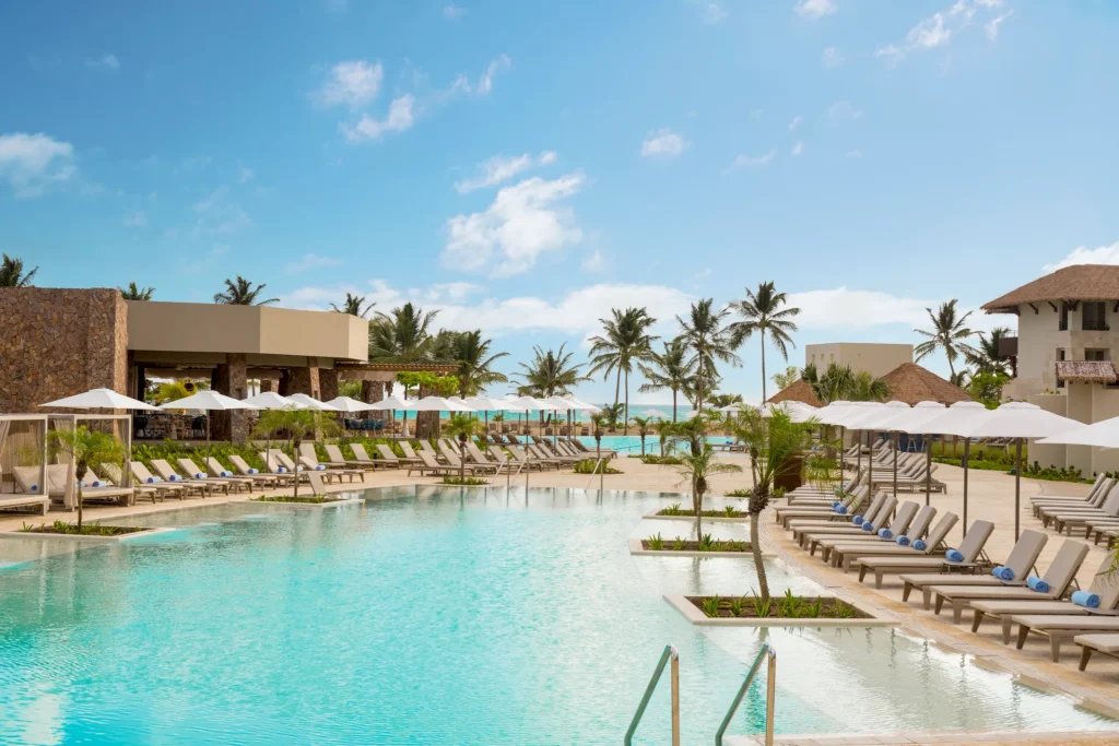 Peaceful resort pool lined with loungers and palm trees at Dreams Playa Esmeralda Resort & Spa.